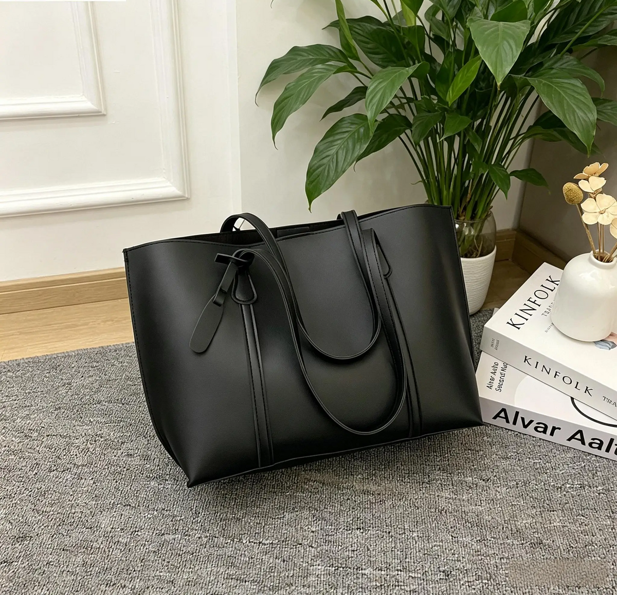 Petit sac fourre-tout aspect cuir noir posé au sol
