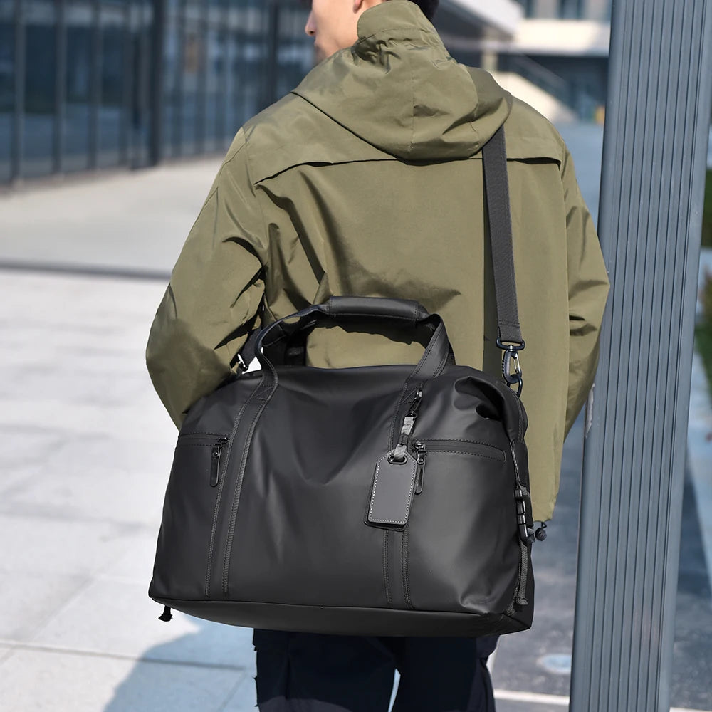 Sac de voyage homme noir porté à l'épaule avec la bandoulière
