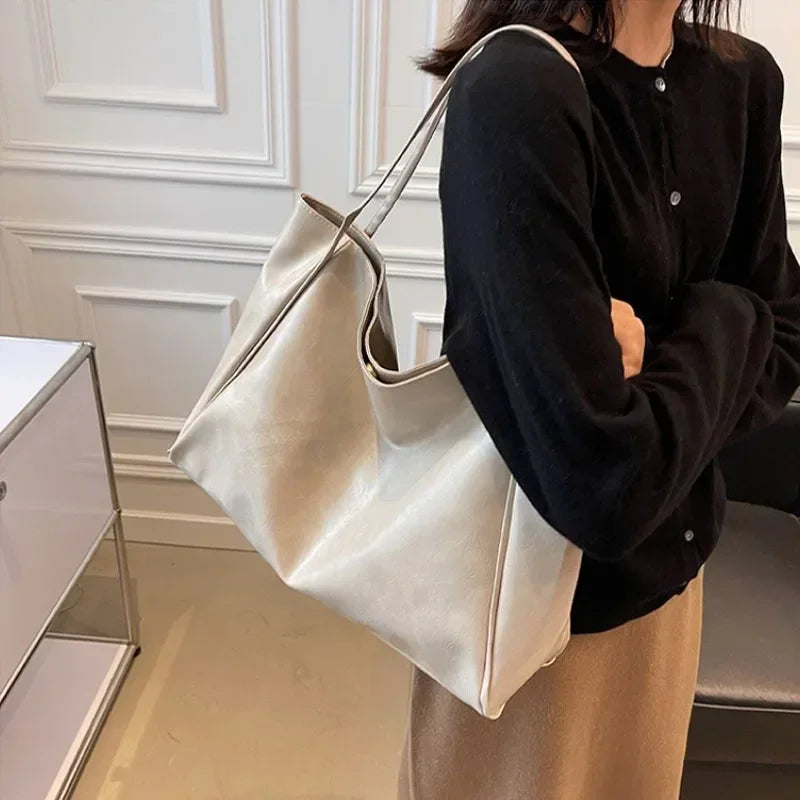 Sac seau aspect cuir souple blanc crème porté à l'épaule