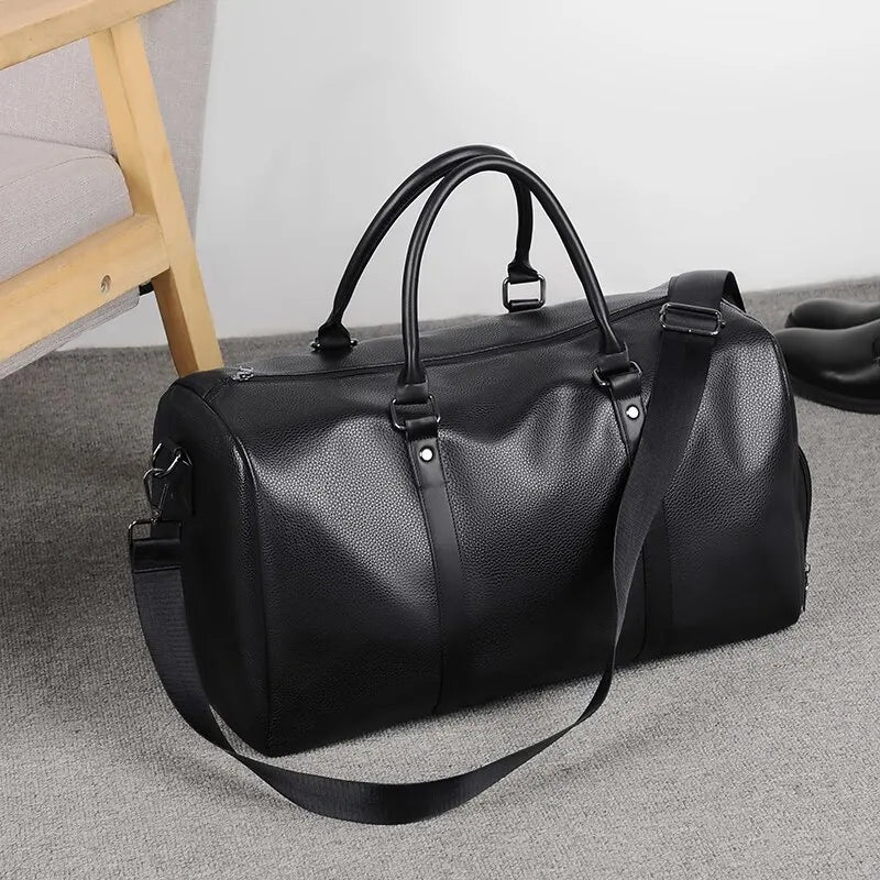 Sac de voyage aspect cuir rétro noir posé au sol avec sa bandoulière