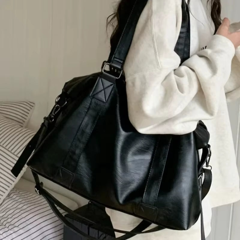 Sac fourre-tout aspect cuir noir porté à l'épaule, vue de côté