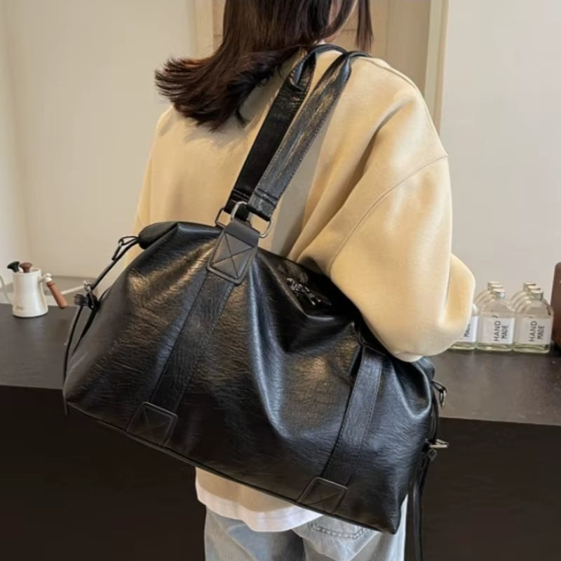 Sac fourre-tout aspect cuir noir porté à l'épaule