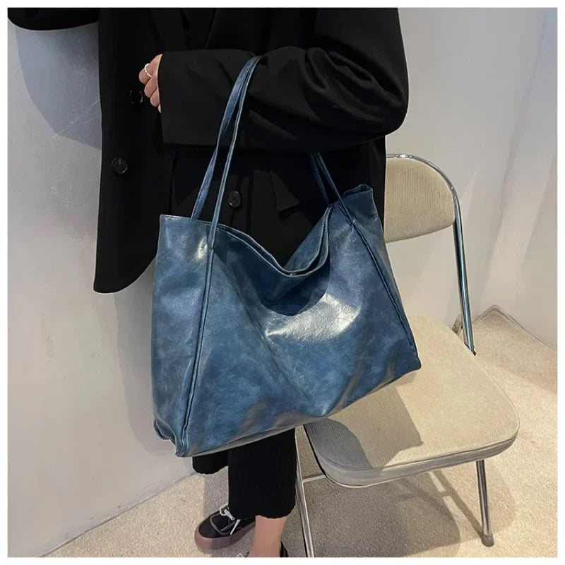 Sac seau aspect cuir souple bleu porté à l'épaule