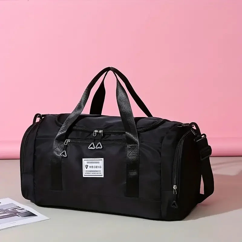 Sac de voyage pliable noir posé devant un fond rose