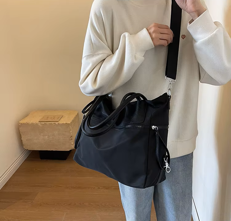 Sac bandoulière nylon noir porté avec la sangle longue