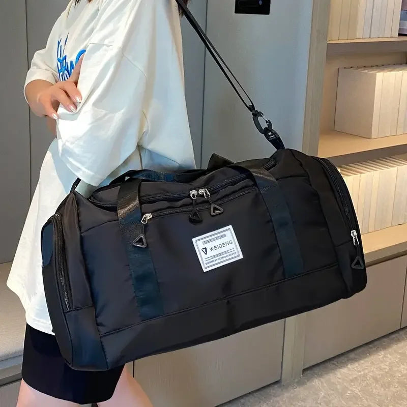 Sac de voyage pliable noir porté à l'épaule, vue de côté
