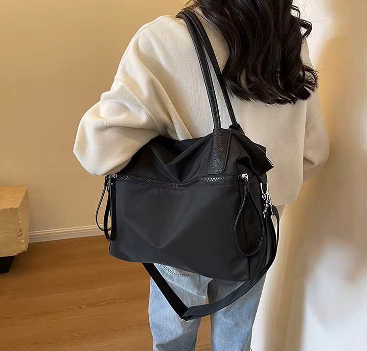 Sac bandoulière nylon noir porté à l'épaule, vue de dos