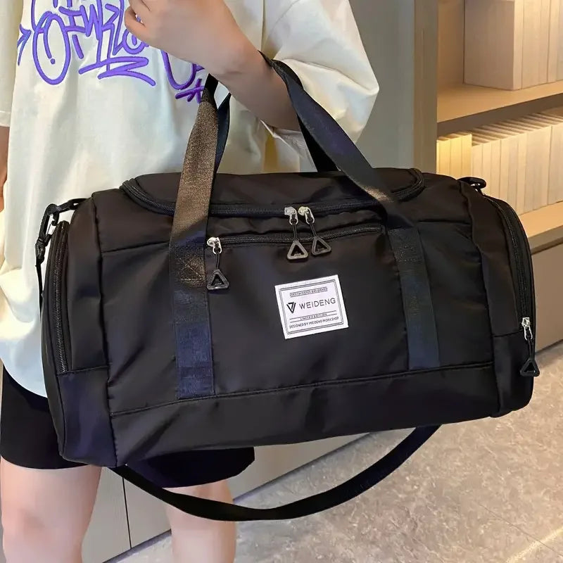 Sac de voyage pliable noir tenu par ses anses, vue rapprochée