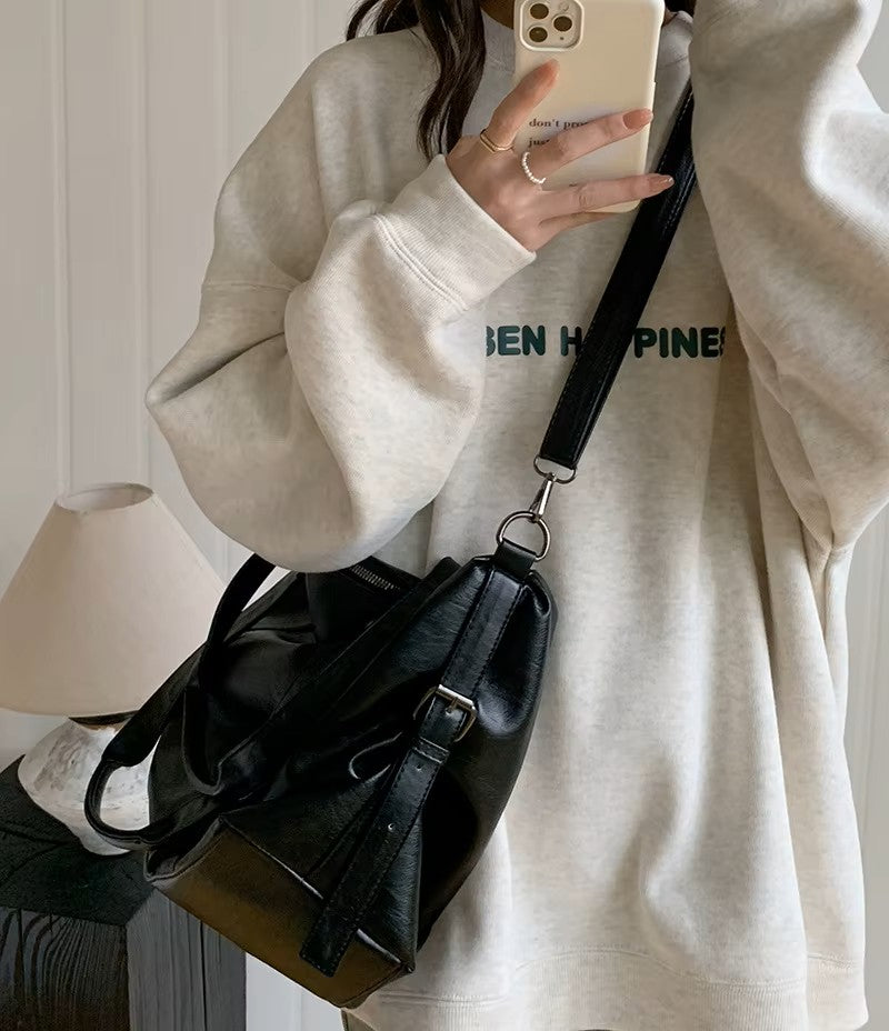 Sac fourre-tout aspect cuir noir porté en bandoulière