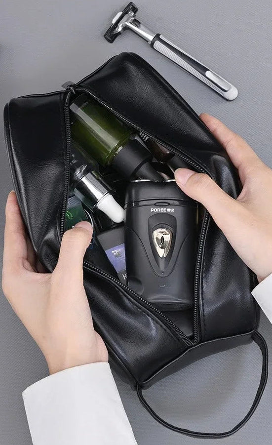 Trousse de toilette noire ouverte à deux mains, remplie de flacons et d'un rasoir électrique