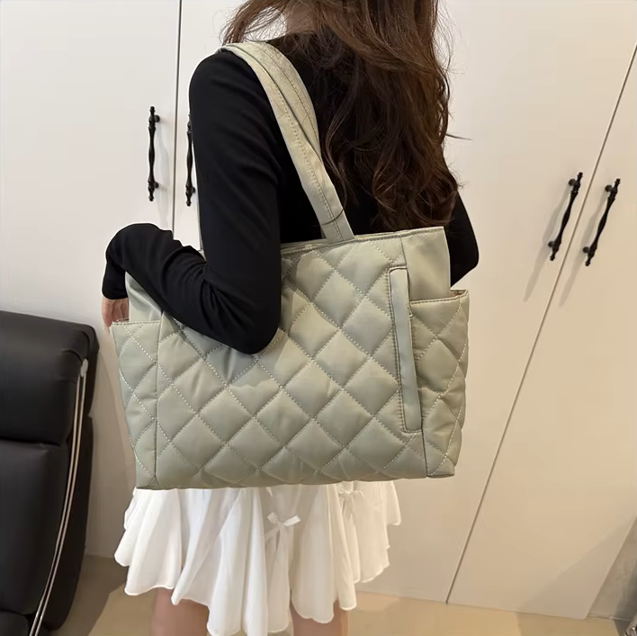 Cabas matelassé vert porté à l'épaule, sac cabine femme