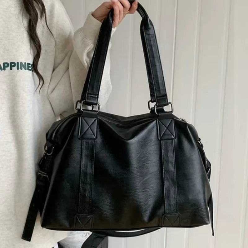 Sac fourre-tout aspect cuir noir tenu par les anses