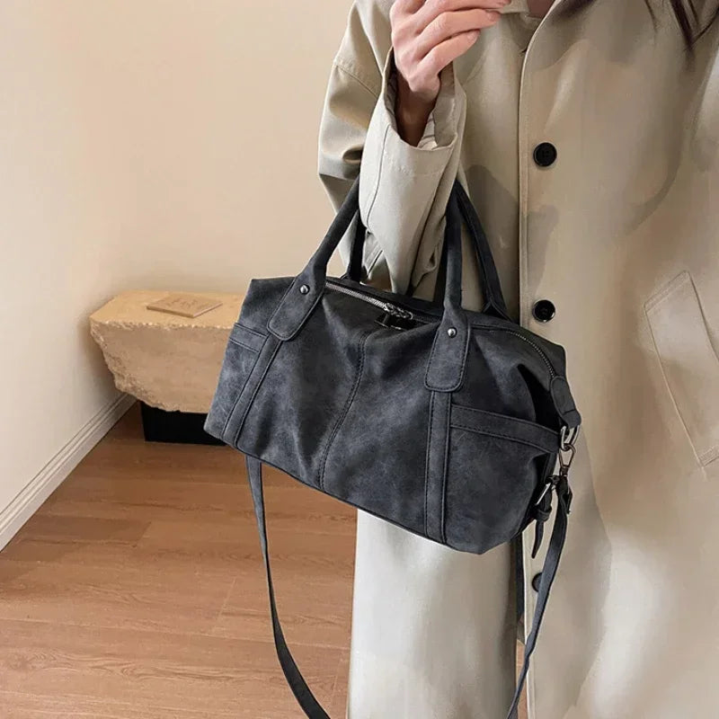 Sac aspect cuir rétro noir texturé porté à la main