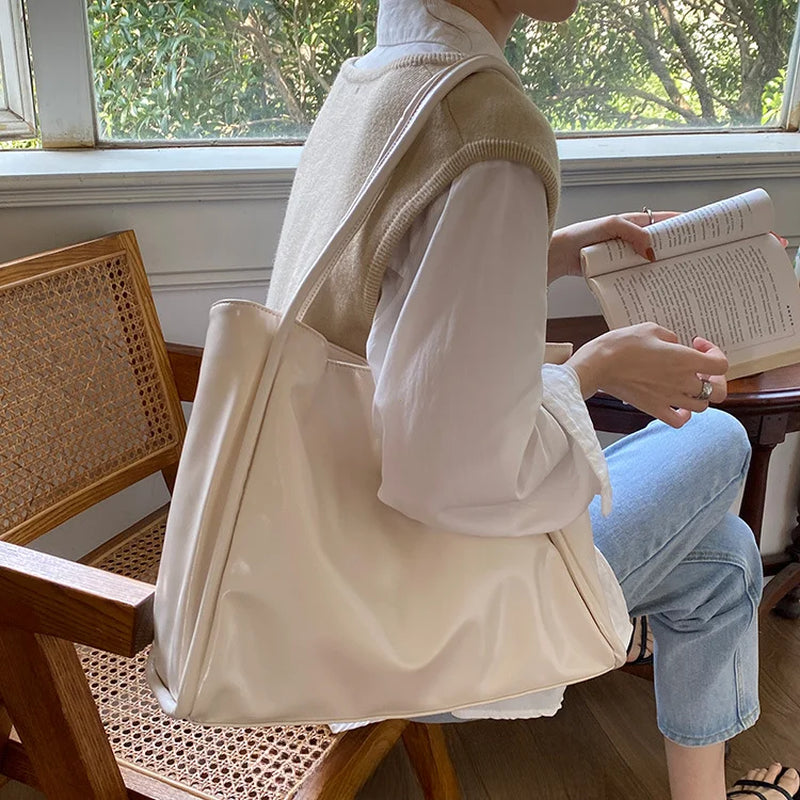 Sac cabas texturé beige porté à l'épaule en position assise