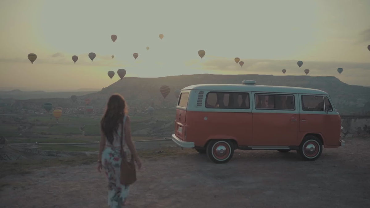 Voyageuse devant un van, montgolfières au coucher du soleil